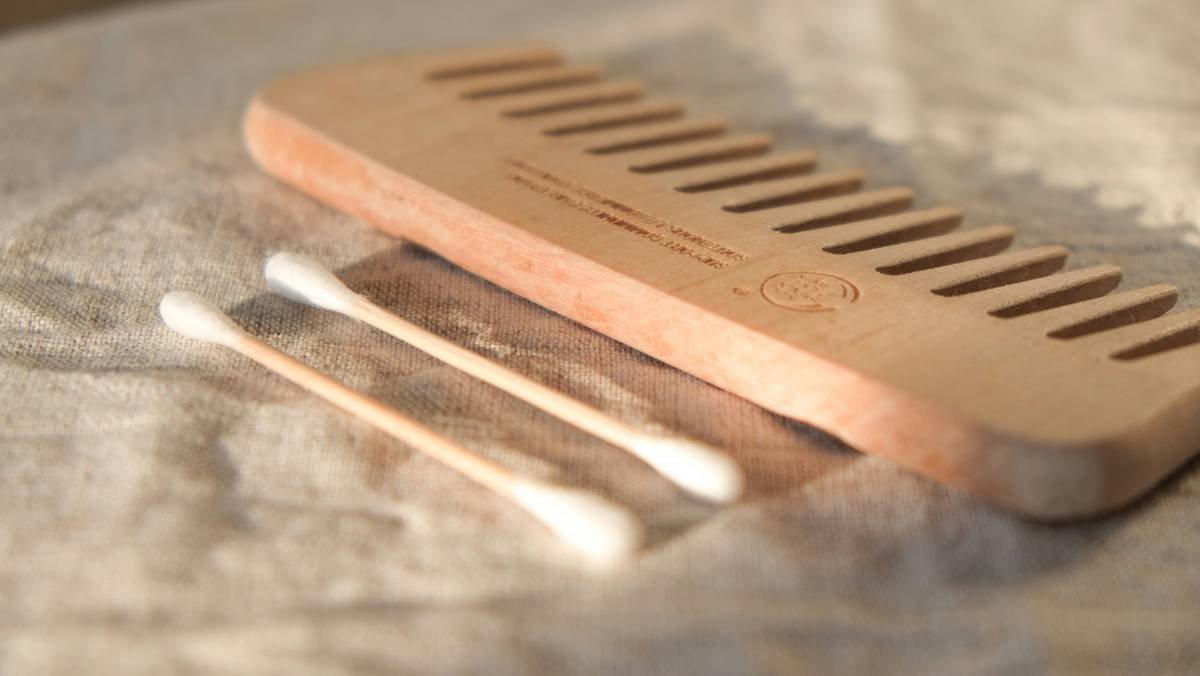 Side-by-side comparison: cheap plastic comb vs. premium wooden comb and boar bristle brush showing reduced hair breakage and smooth texture