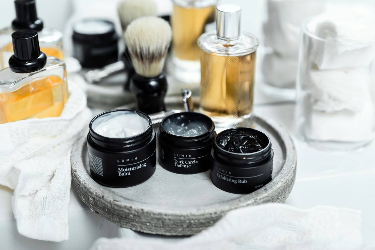 beard care and styling essentials kit laid out on wooden surface with oil, balm, brush, and comb